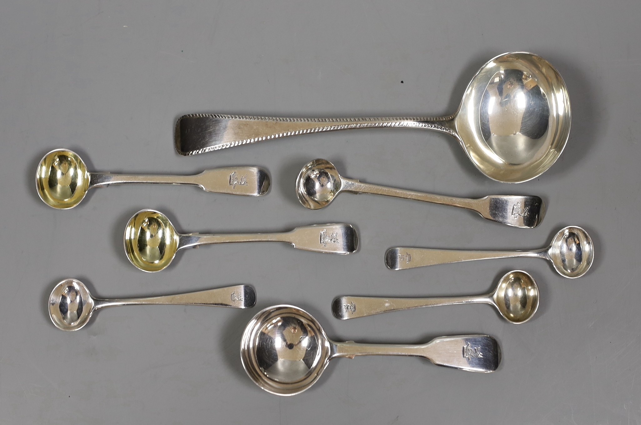 A composite set of six George III Old English pattern and fiddle pattern spoons for condiments, a William IV silver caddy spoons and a Victorian silver sauce ladle, 5.2oz